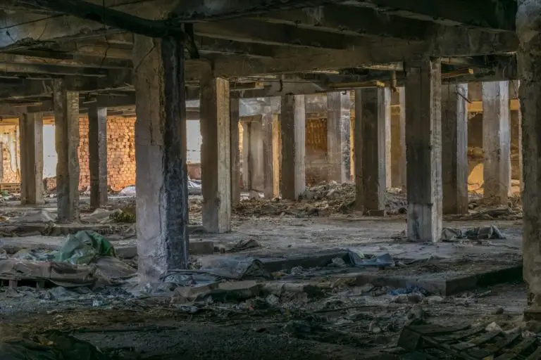 Abandoned industrial space with dilapidated columns and scattered debris, enveloped in a quiet atmosphere.