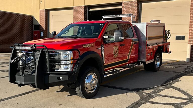 Red Ford F-550 brush fire truck parked in front of a fire station.