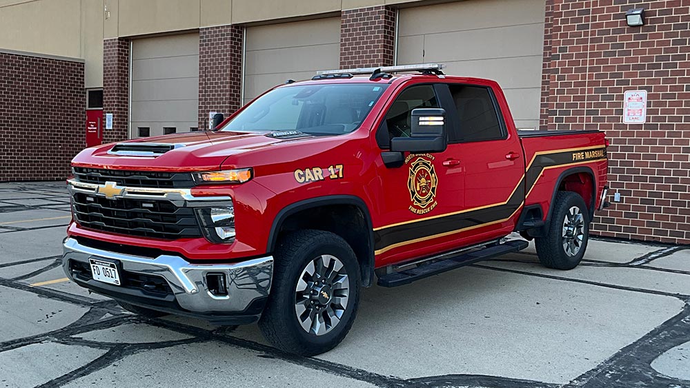 A red North Ridge City Fire Rescue EMS pickup truck labeled “Car 17” and “Fire Marshal” parked in front of a brick building.