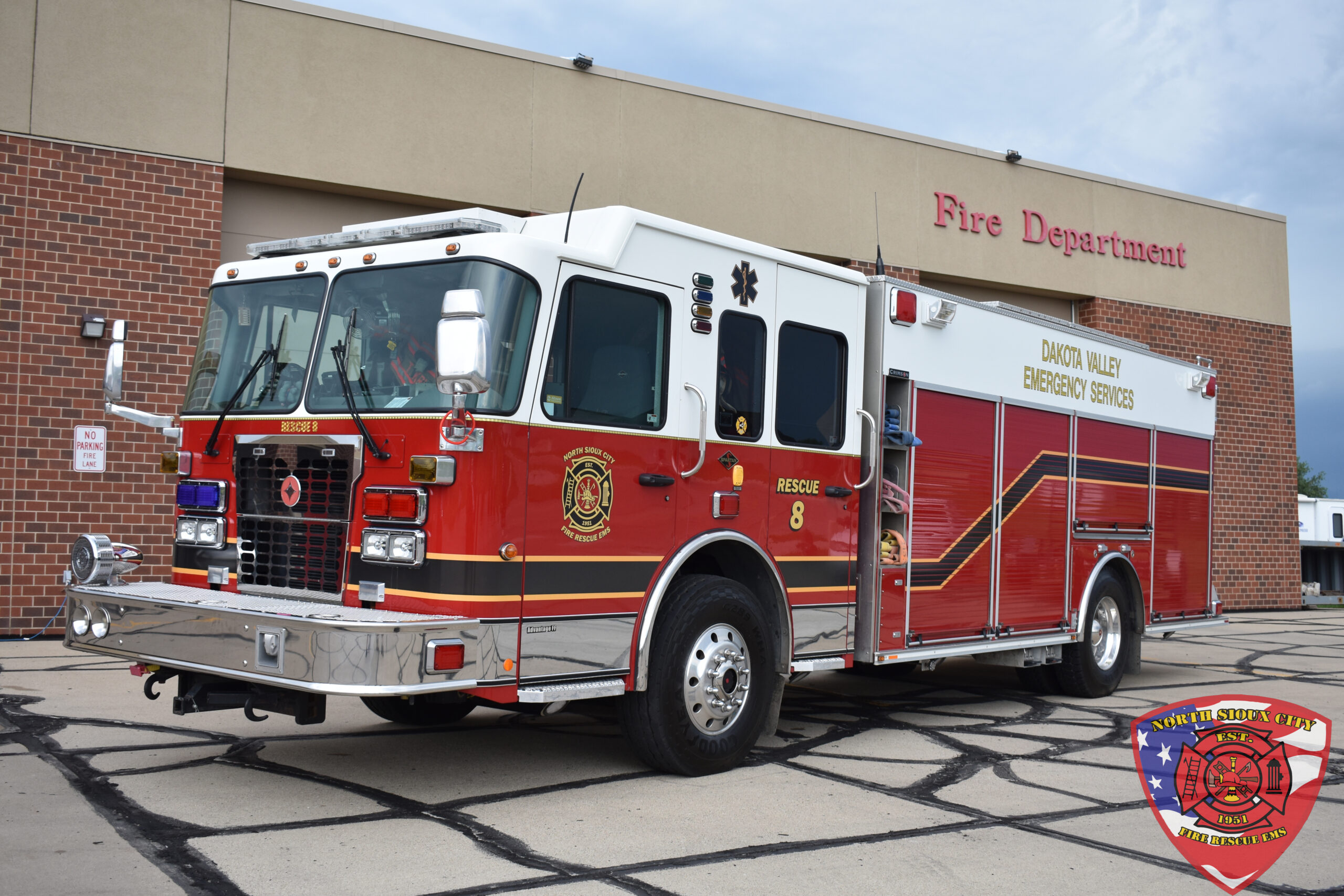A red and white Dakota Valley Emergency Services fire rescue truck parked in front of a fire station.